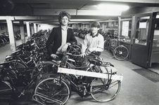 405416 Afbeelding van M. Boerings (links, beheerder fietsenstalling) en een medewerker in de fietsenstalling onder de ...